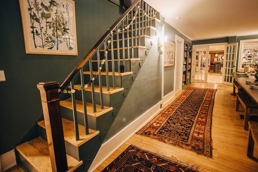Cozy hallway with stairs, patterned rug, and soft lighting.
