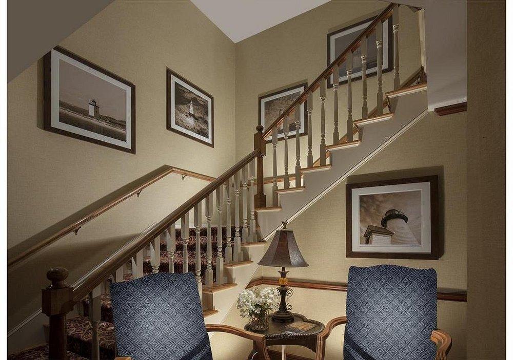 Staircase with framed art, two chairs, and a lamp.