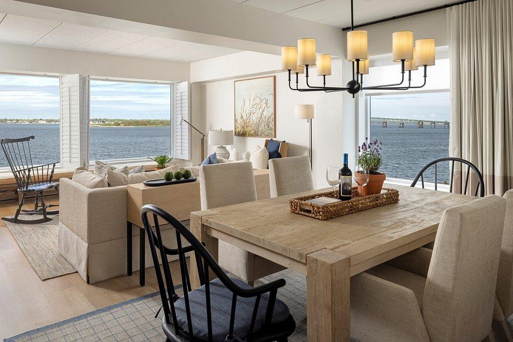 Dining room with wooden table, black chairs, and a view of the water outside.