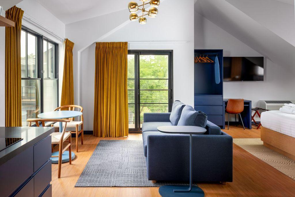 Bright modern apartment with blue sofa, yellow curtains, and a wall-mounted TV.