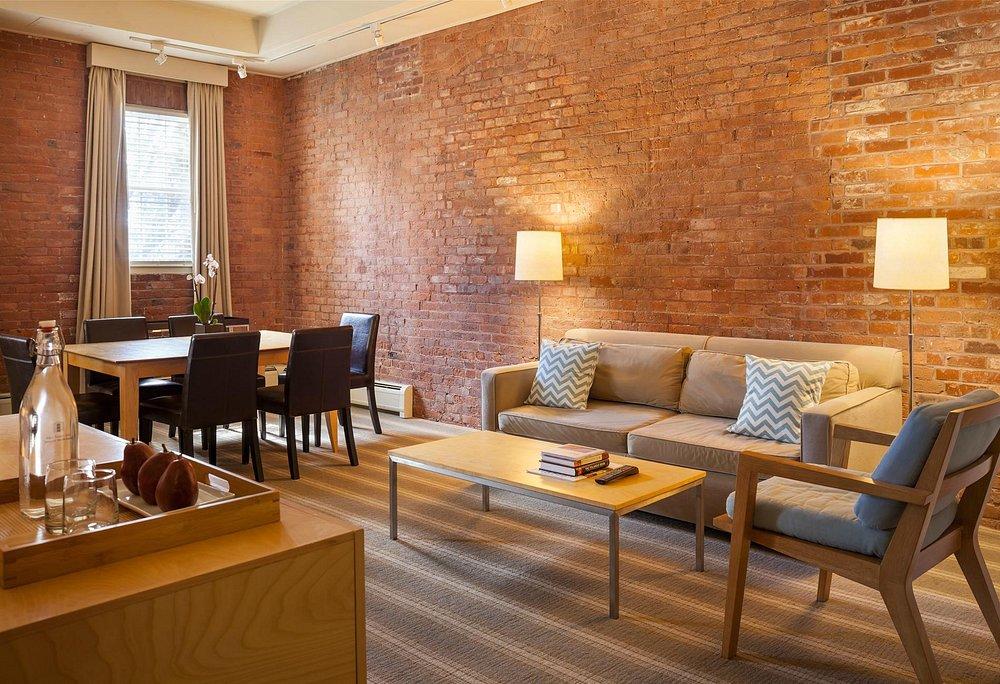 Living room with brick walls, sofa, dining table, and soft lighting.