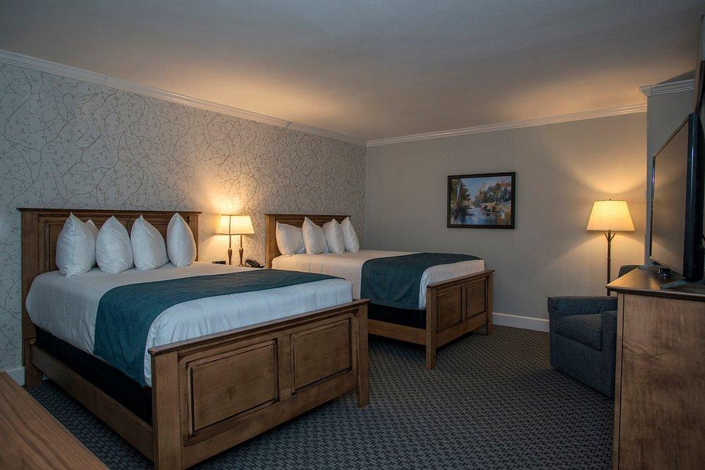 Hotel room with two queen beds, wooden furniture, and soft lighting.