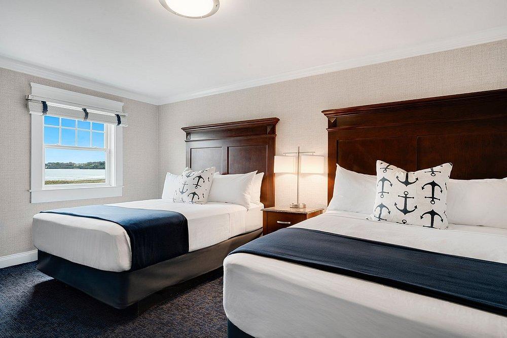 Two neatly made beds with navy accents in a bright hotel room.