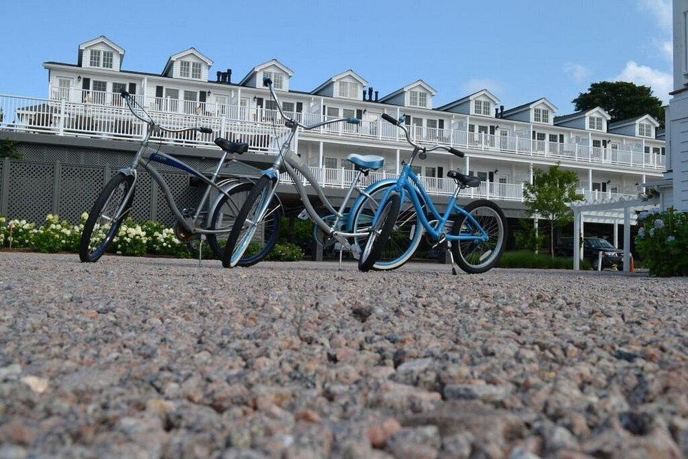 Bicycles parked on gravel, with a large white building in the background.