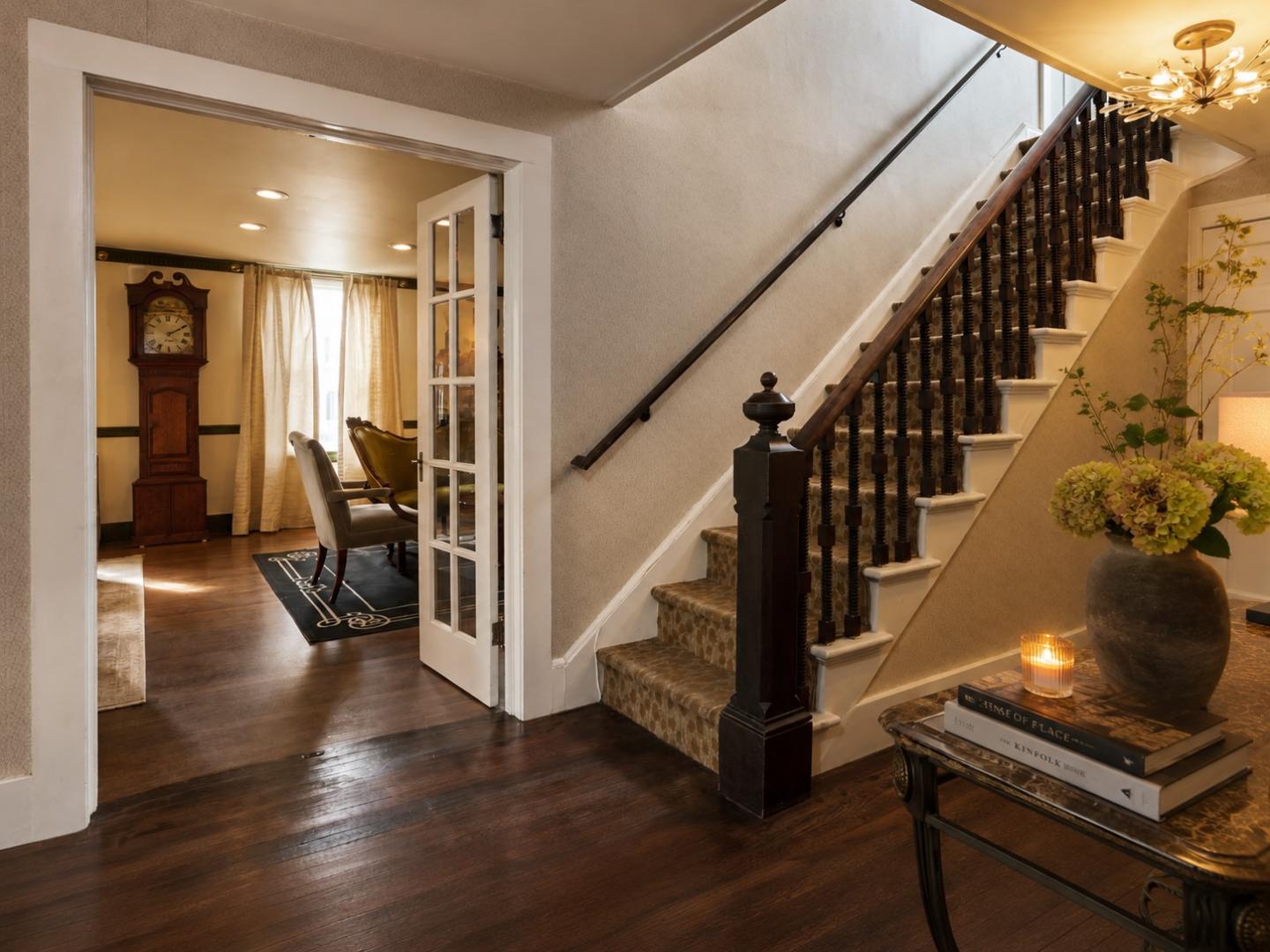 Cozy hallway with wooden stairs, potted plant, and warm lighting.