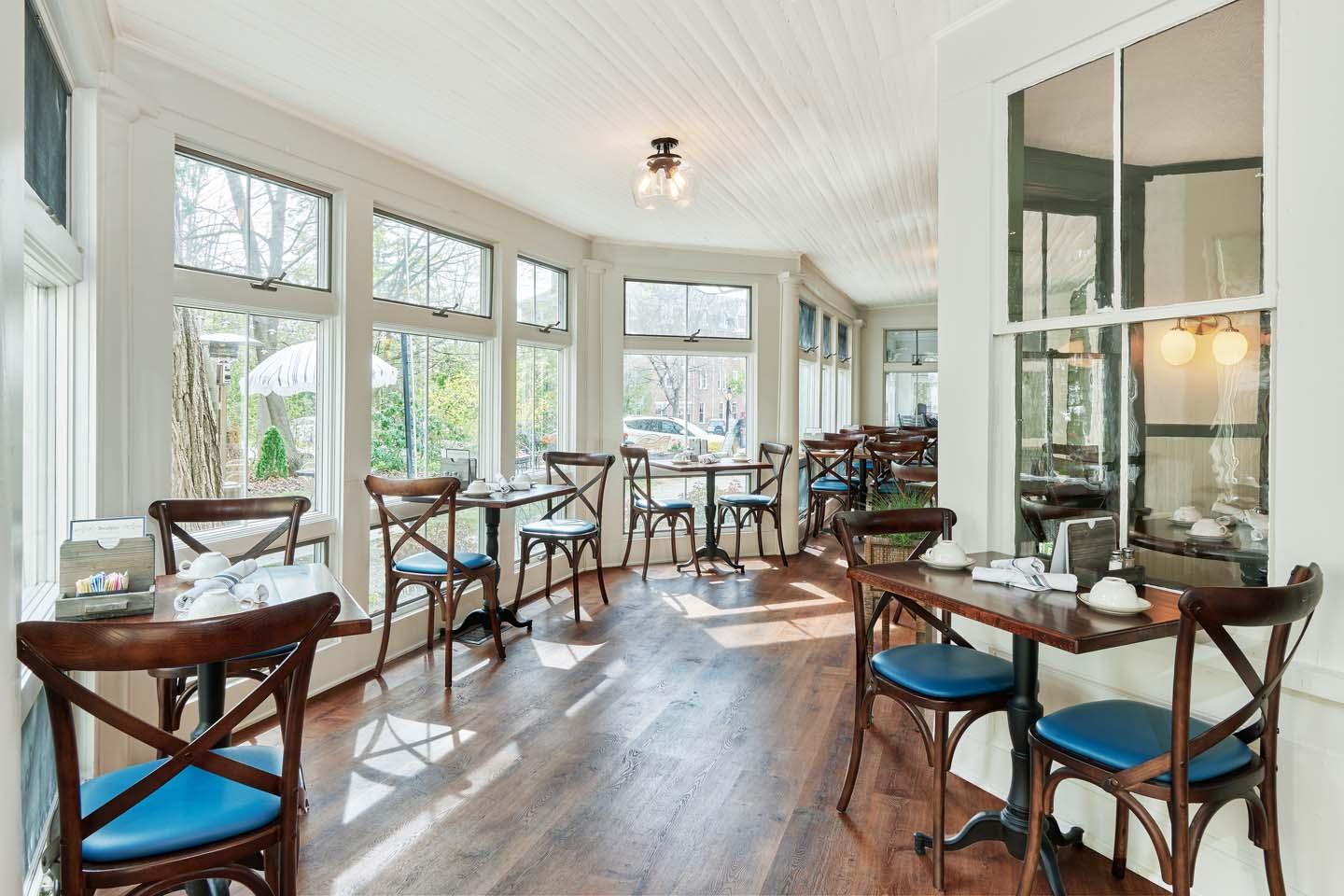 Bright cafe with wooden tables, blue chairs, and large windows.