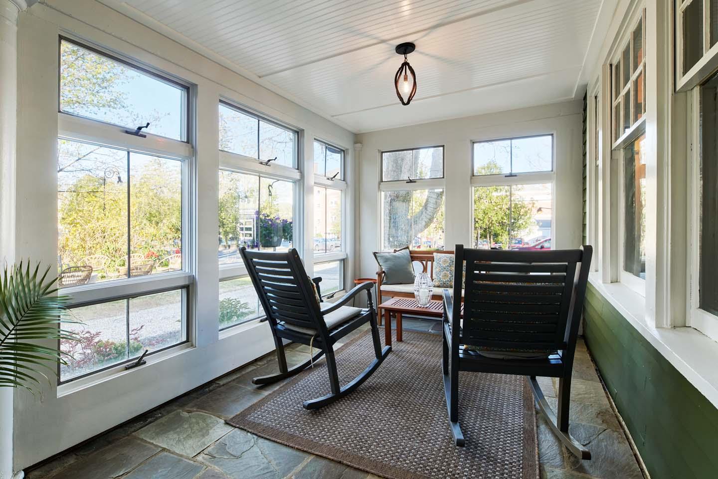 Sunny porch with two rocking chairs and a small table.