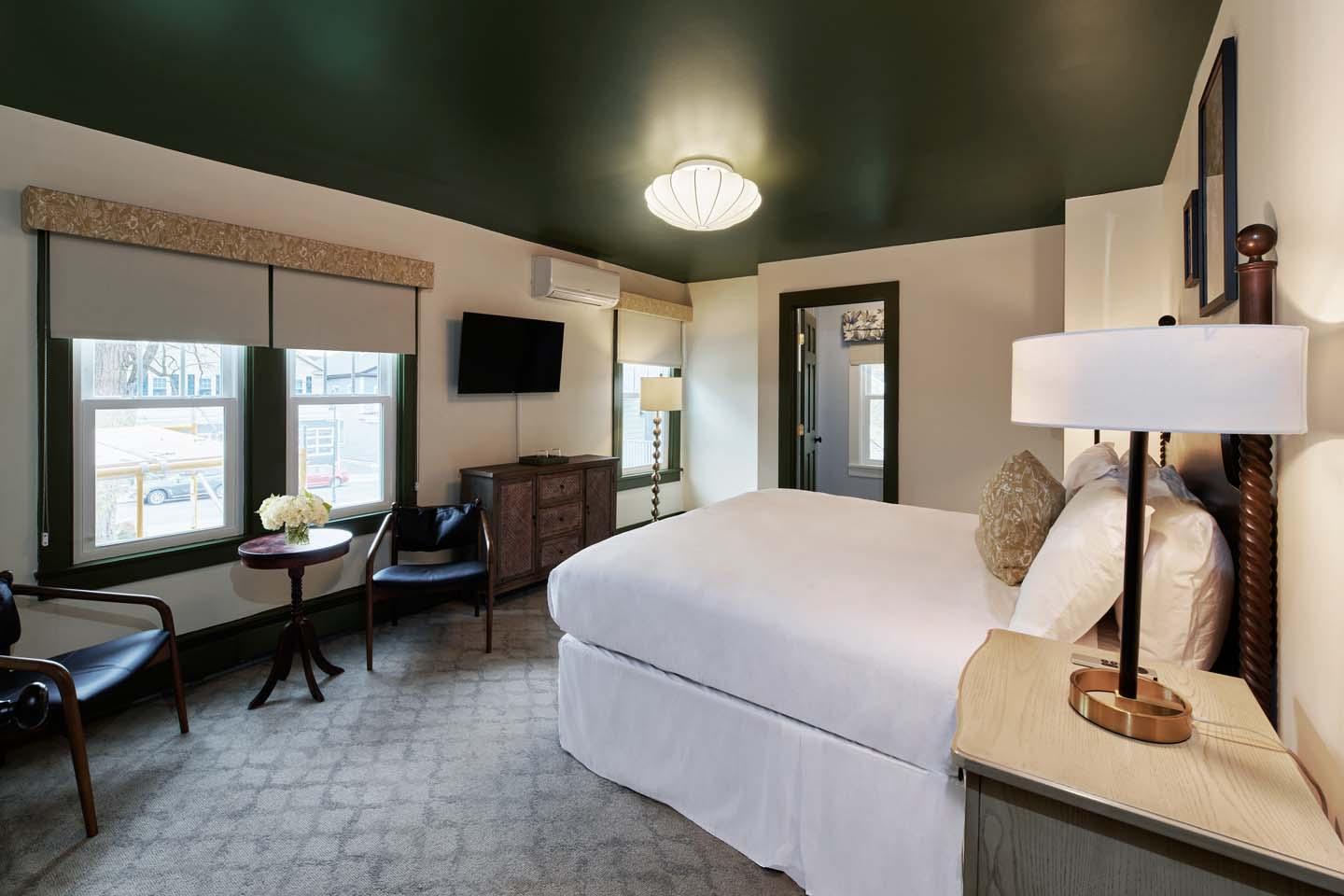 Cozy hotel room with a double bed, chairs, and a TV on the wall.