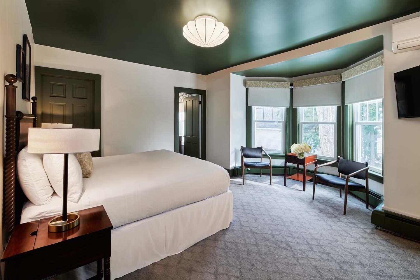 Cozy hotel room with a large bed, two chairs, and a bright window.