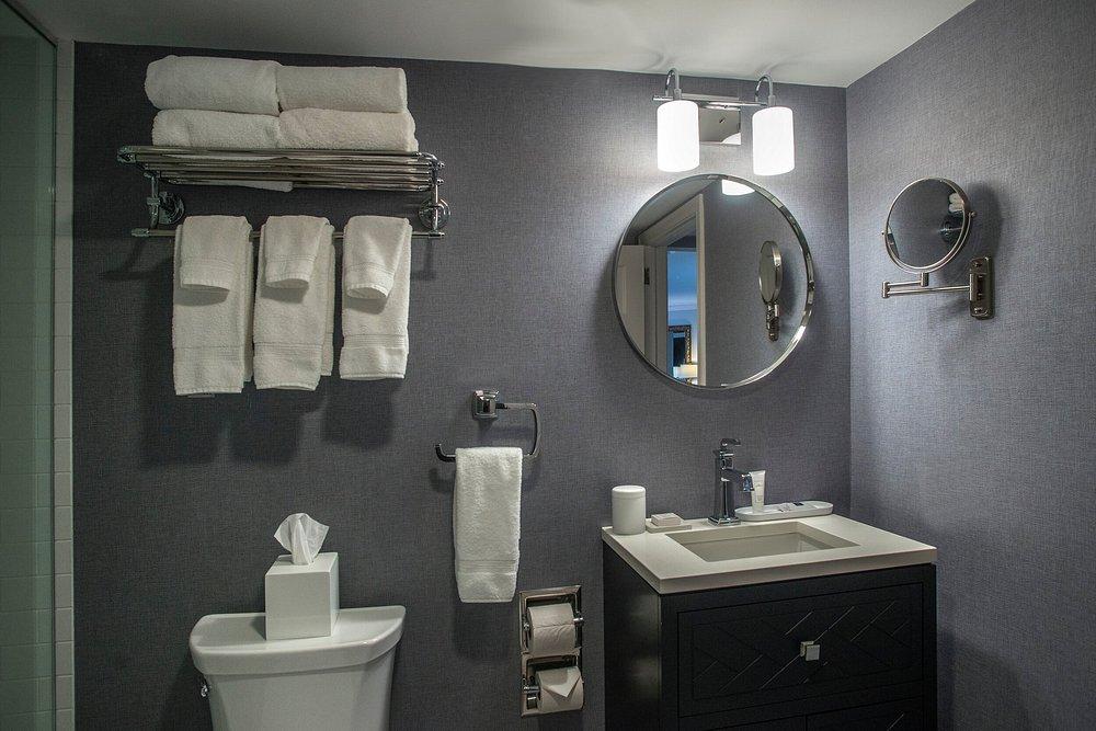 Modern bathroom with towels, circular mirror, and black vanity.