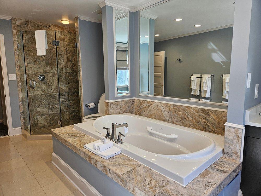 Luxurious bathroom with a marble bathtub and glass shower.