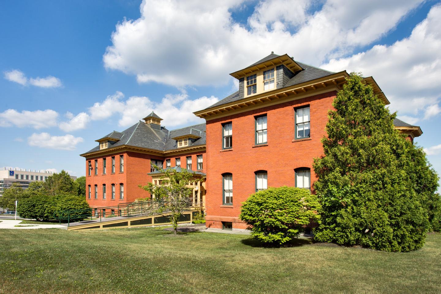 Historic red brick building with a dark roof under a blue sky.