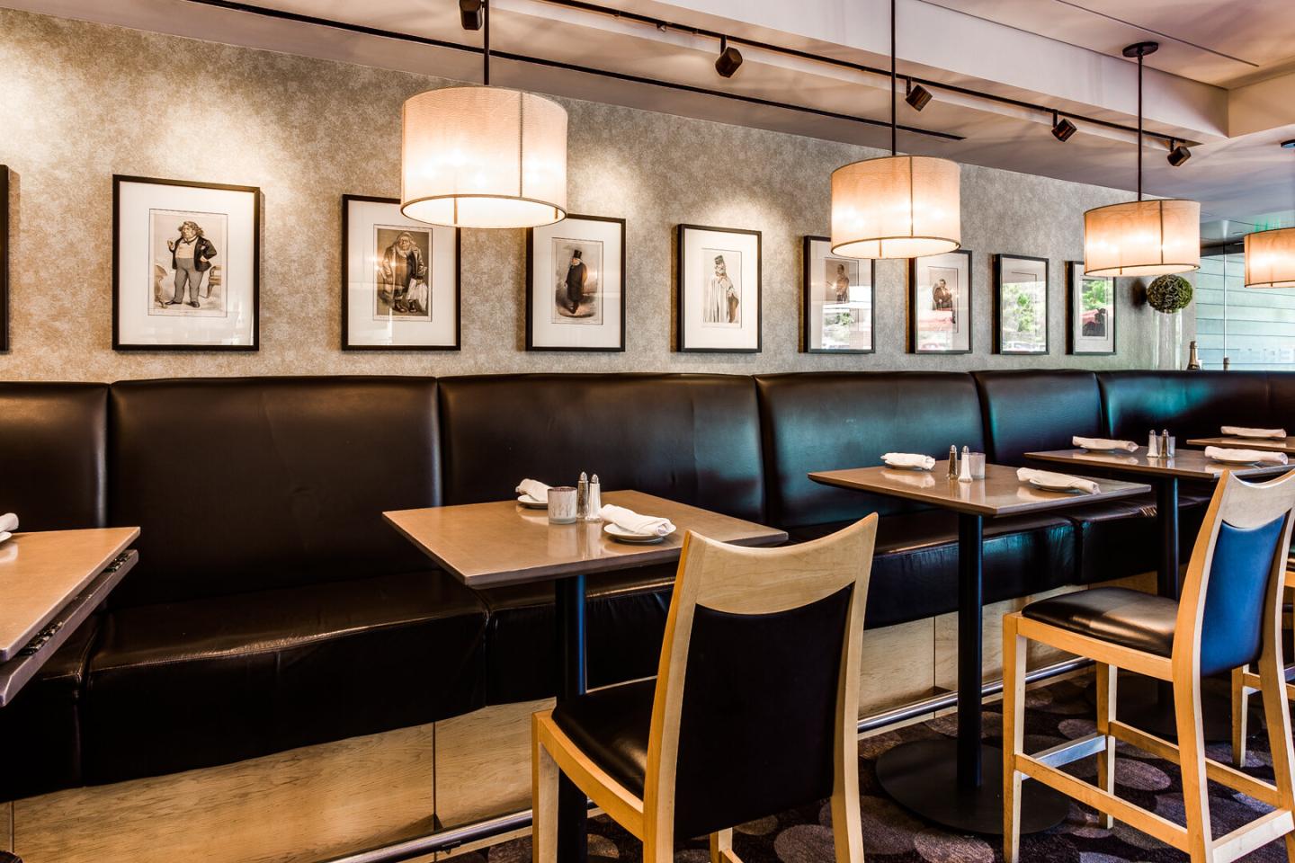 Modern restaurant with framed art, hanging lights, and wooden chairs.