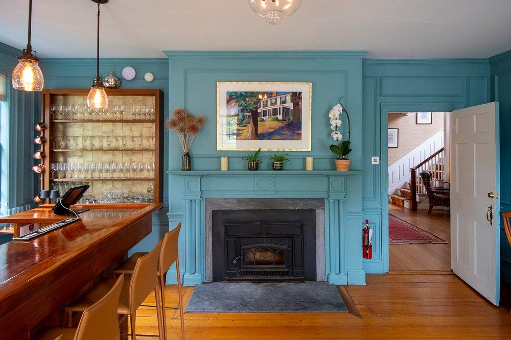 Cozy room with blue walls, fireplace, and a wooden bar counter with hanging lights.