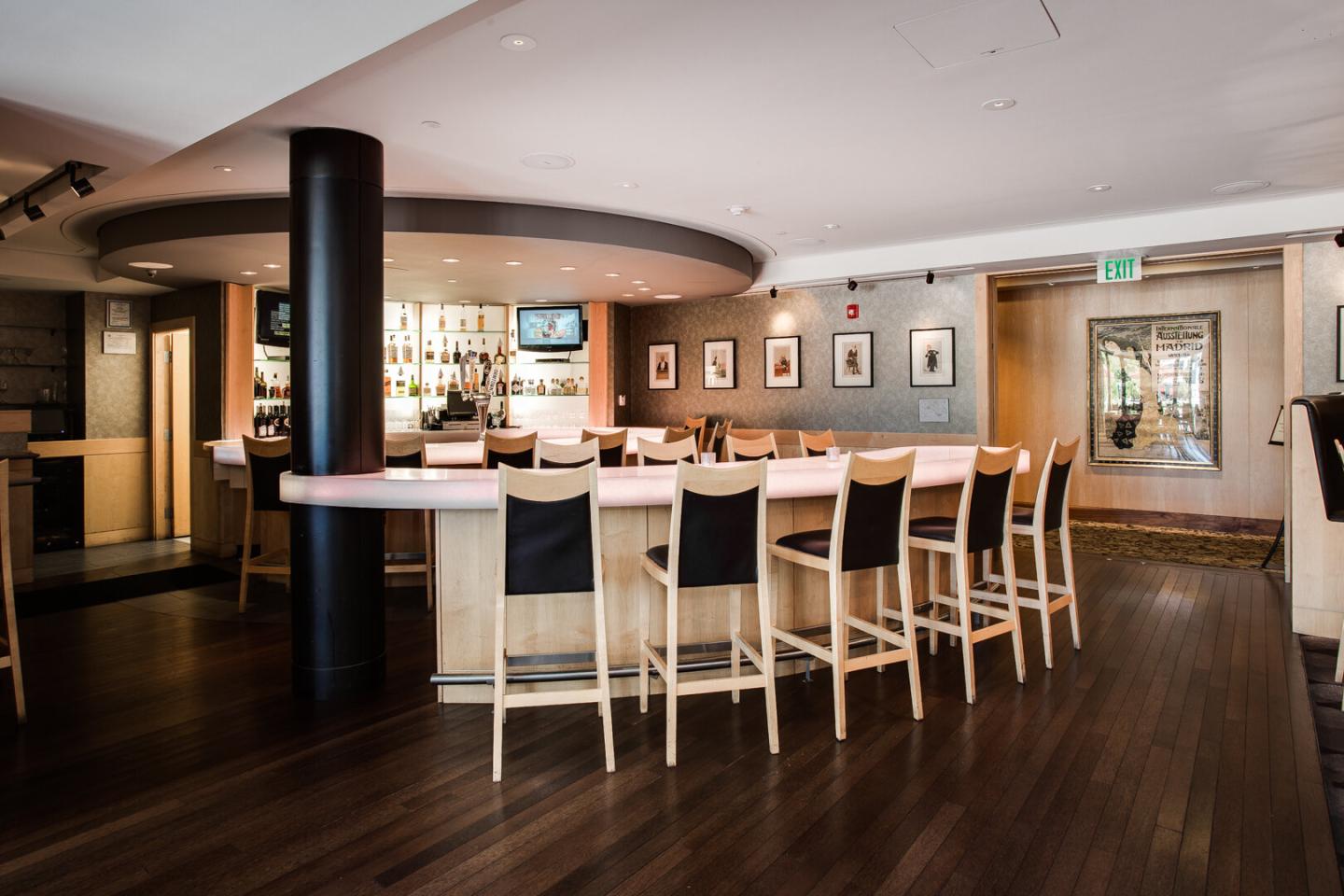 Sleek modern bar with high chairs and framed photos on walls.