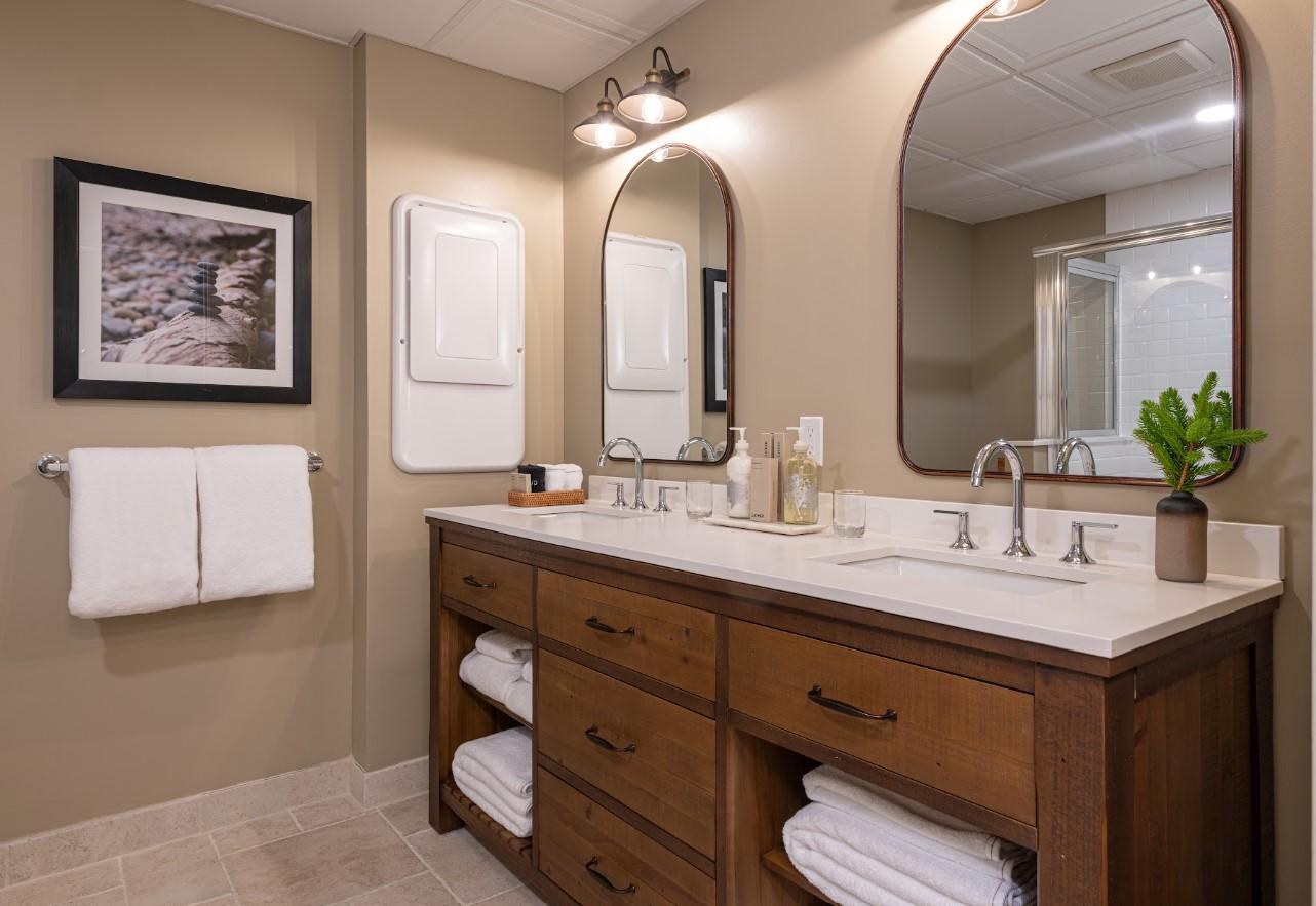 Bathroom with double sink, wooden vanity, and large mirrors.