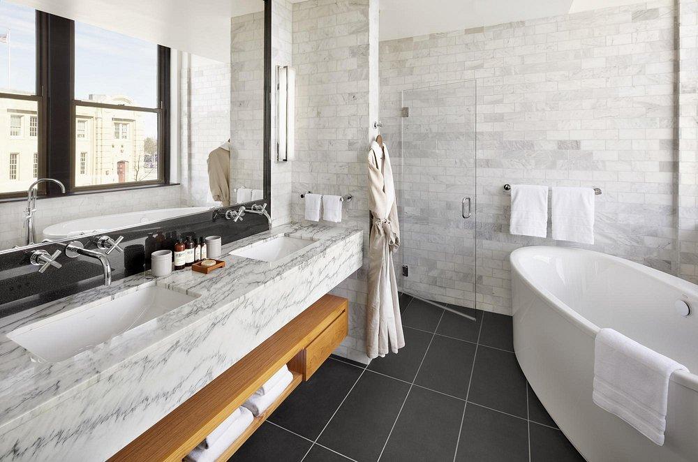 Luxurious bathroom with marble sink, freestanding tub, and large windows.