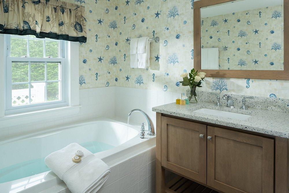 Bathtub and sink in a brightly wallpapered bathroom.