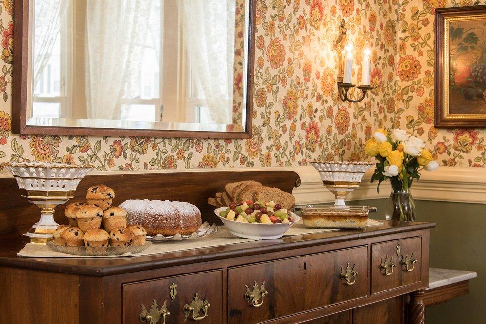 Victorian-style dining room with pastries and fruit on a wooden buffet.