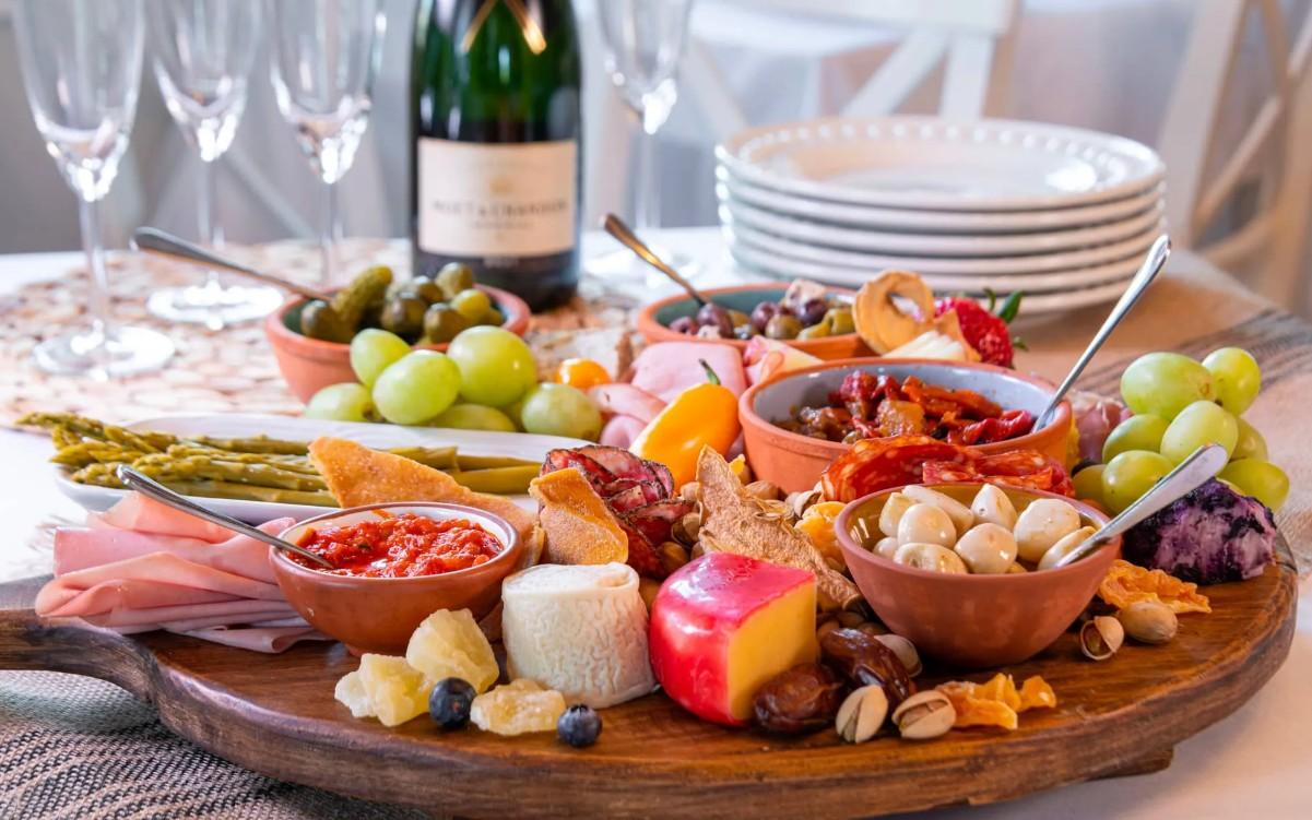 Charcuterie board with cheeses, meats, fruits, and nuts on a round wooden platter.