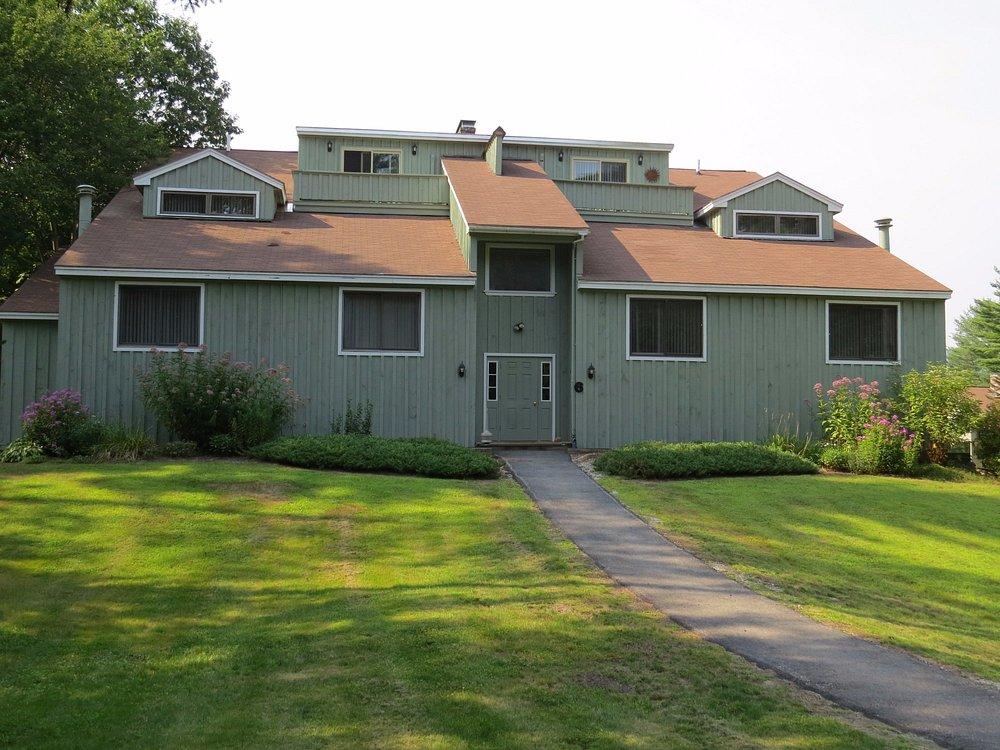 Two-story house with a green lawn and a pathway leading to the entrance.