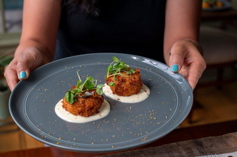 Two crab cakes on a gray plate garnished with greens.