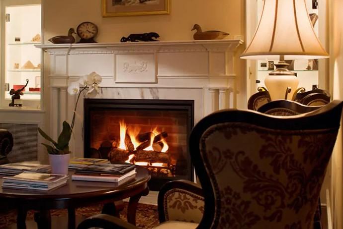 Cozy room with a lit fireplace, armchair, table, and warm lighting.