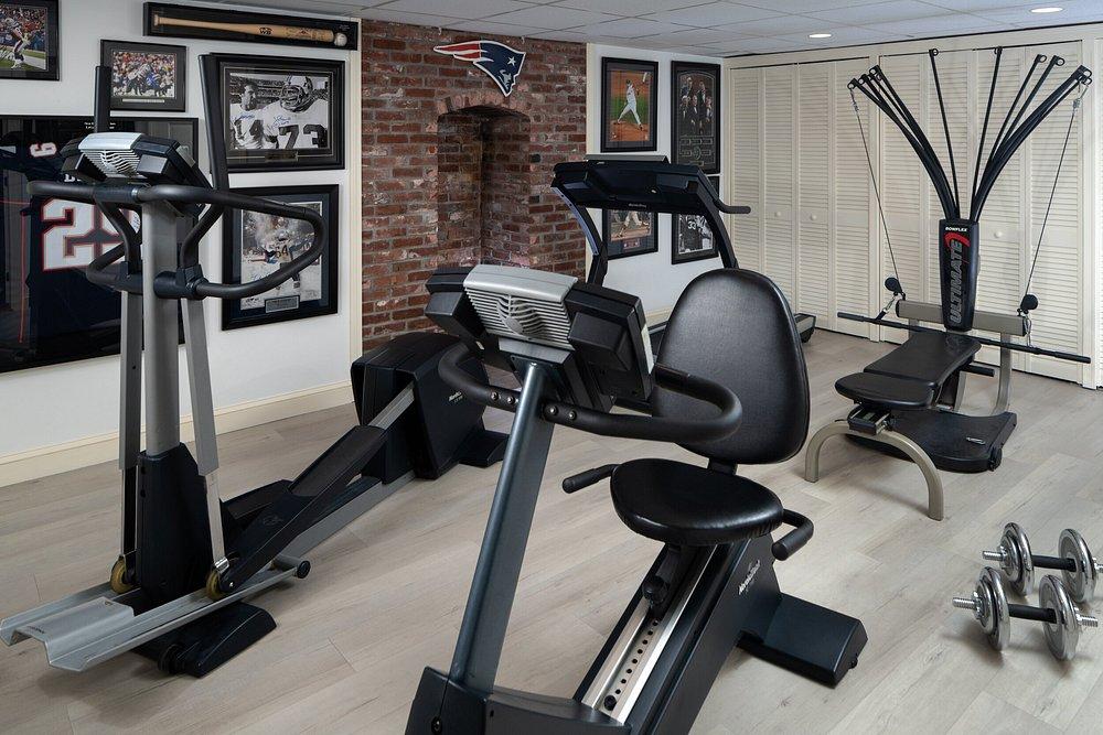 Home gym with exercise equipment, sports memorabilia on walls.