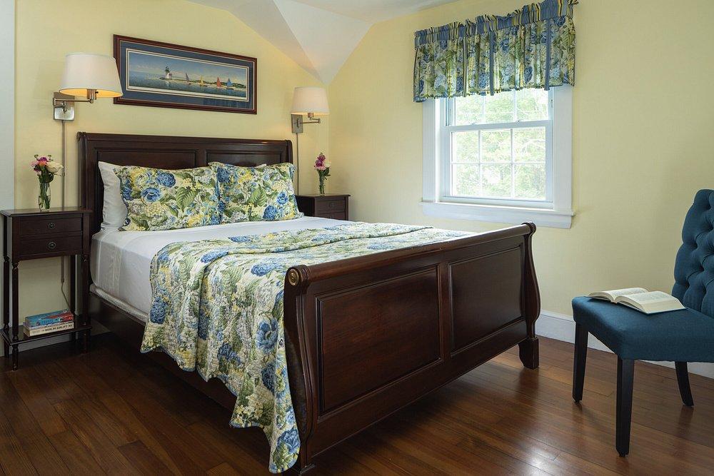 Cozy bedroom with floral bedding, wooden bedframe, and a window with blue curtains.