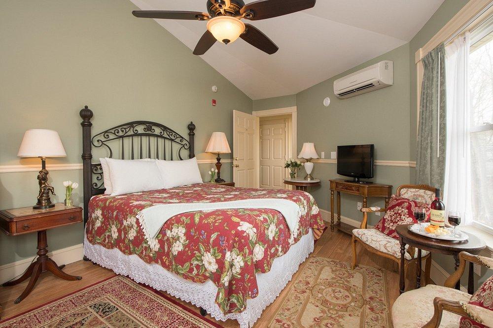 Cozy bedroom with floral bedding, armchairs, and ceiling fan.
