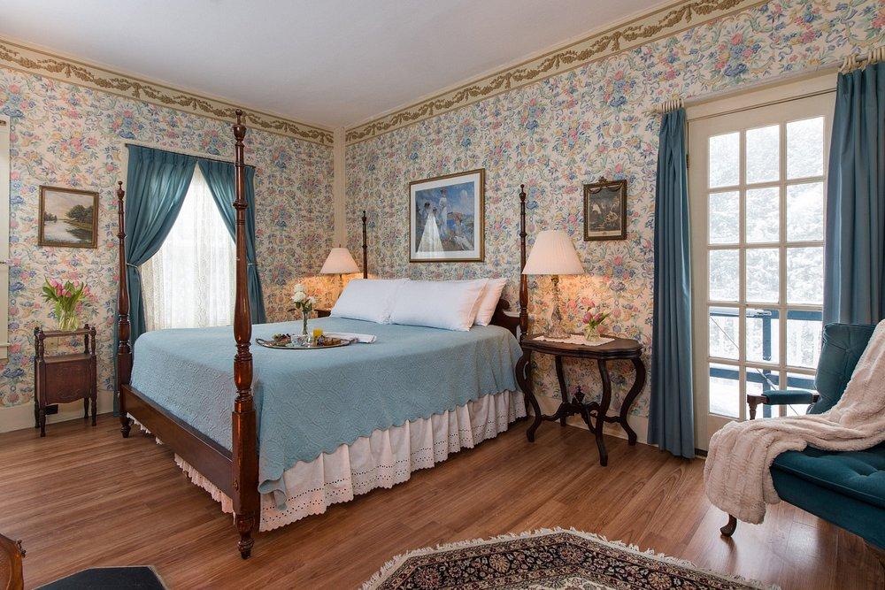 Elegant bedroom with floral wallpaper, a four-poster bed, and soft blue accents.