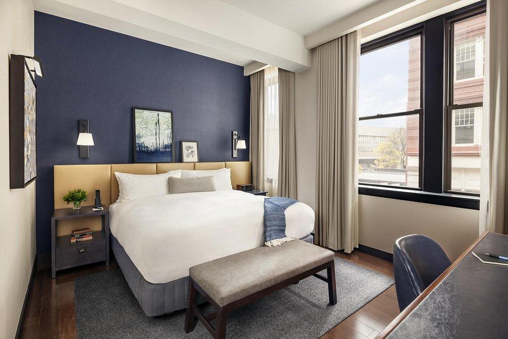 Cozy hotel room with a large bed, navy accent wall, and a city view through the window.