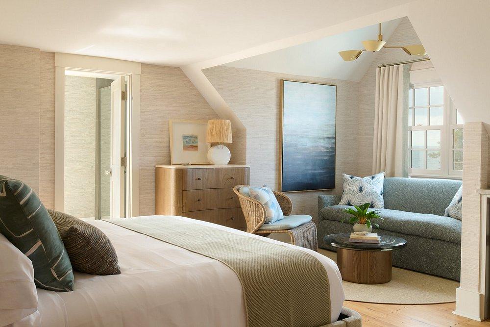 Cozy bedroom with a bed, sofa, dresser, and large painting on the wall.