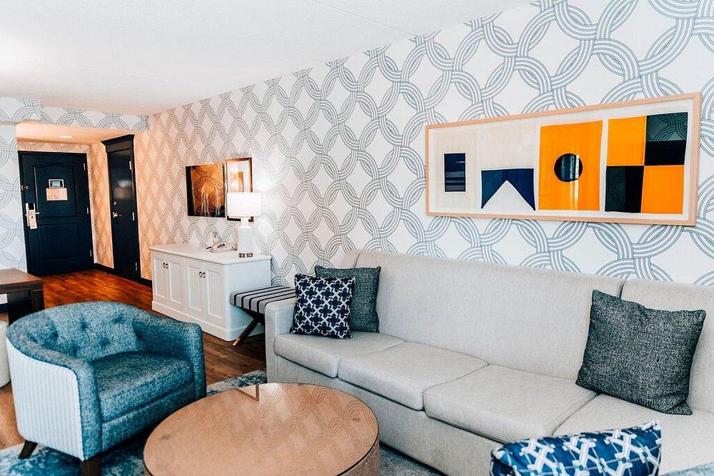 Modern living room with gray sofa, geometric wall art, and blue accents.