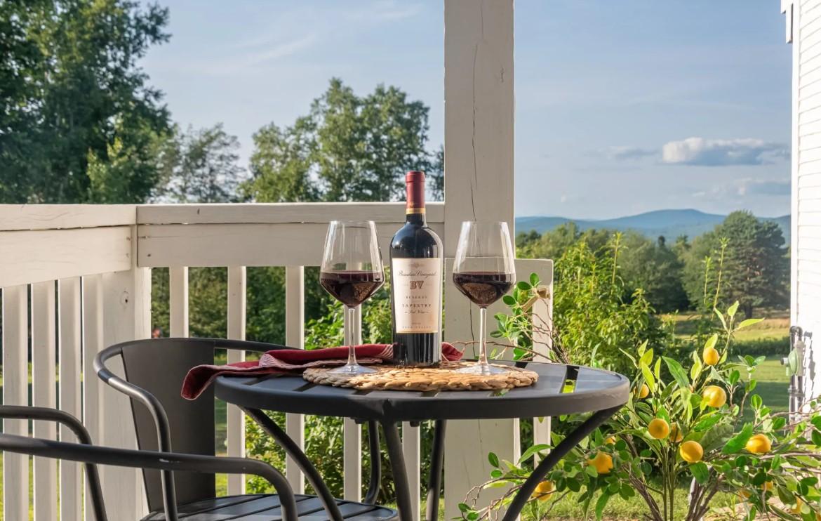 Wine and glasses on a patio table with a scenic view.
