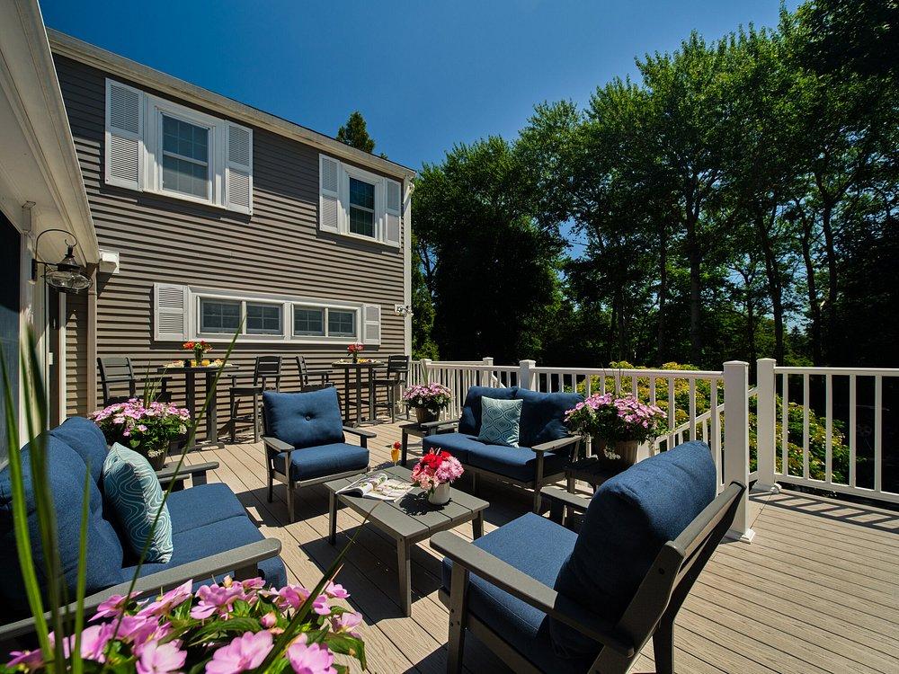 Sunny patio with blue sofas, flowers, and a view of trees.