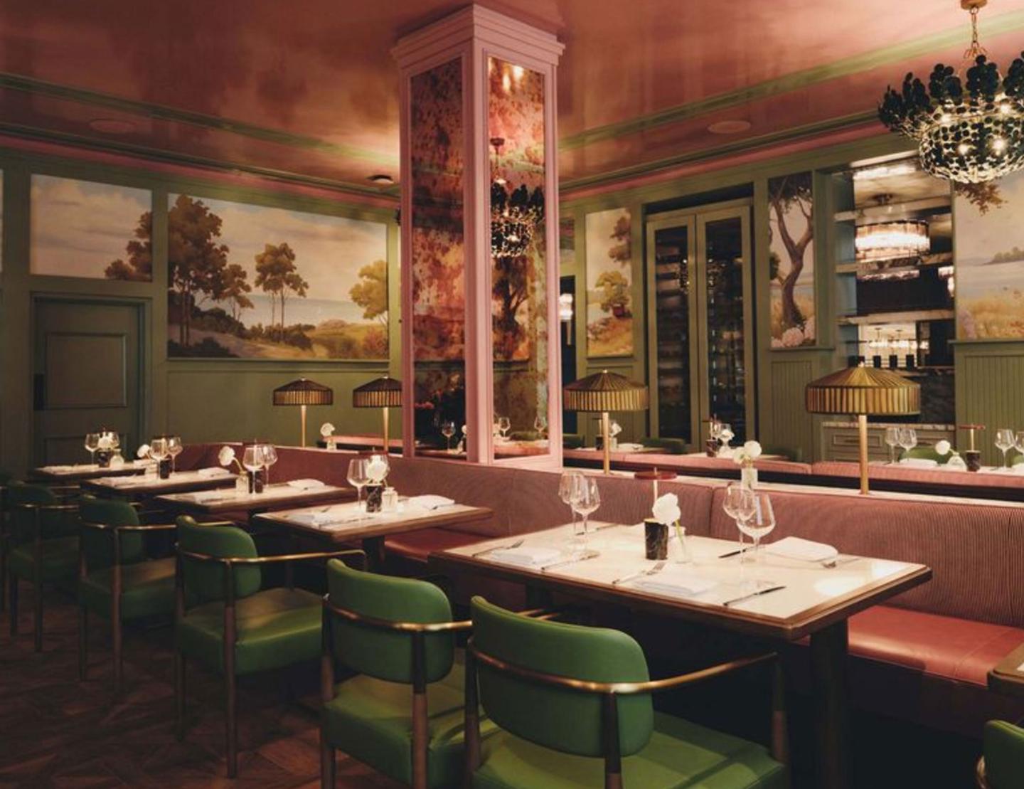 Elegant restaurant interior with green chairs, marble tables, and warm lighting.