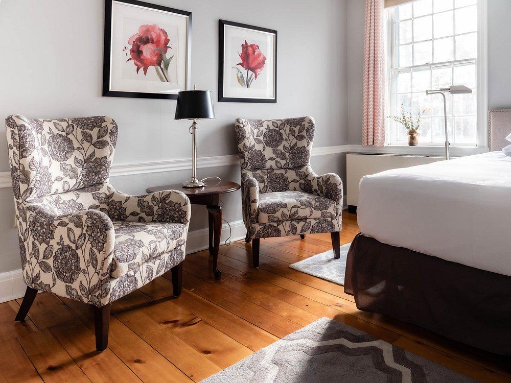 Two floral armchairs with a side table in a bright room.