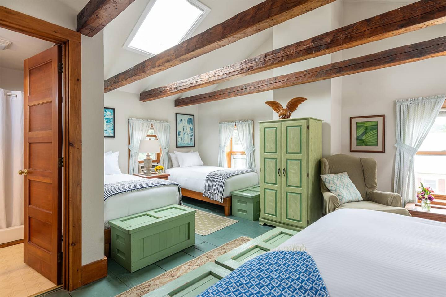 Cozy attic bedroom with two beds, wooden beams, and skylight.