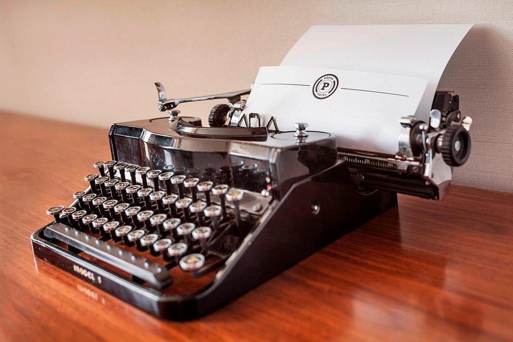 Vintage black typewriter with paper on a wooden desk.