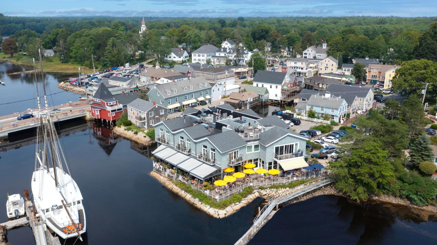 Aerial view of a coastal town with docked ships and colorful buildings by the water.