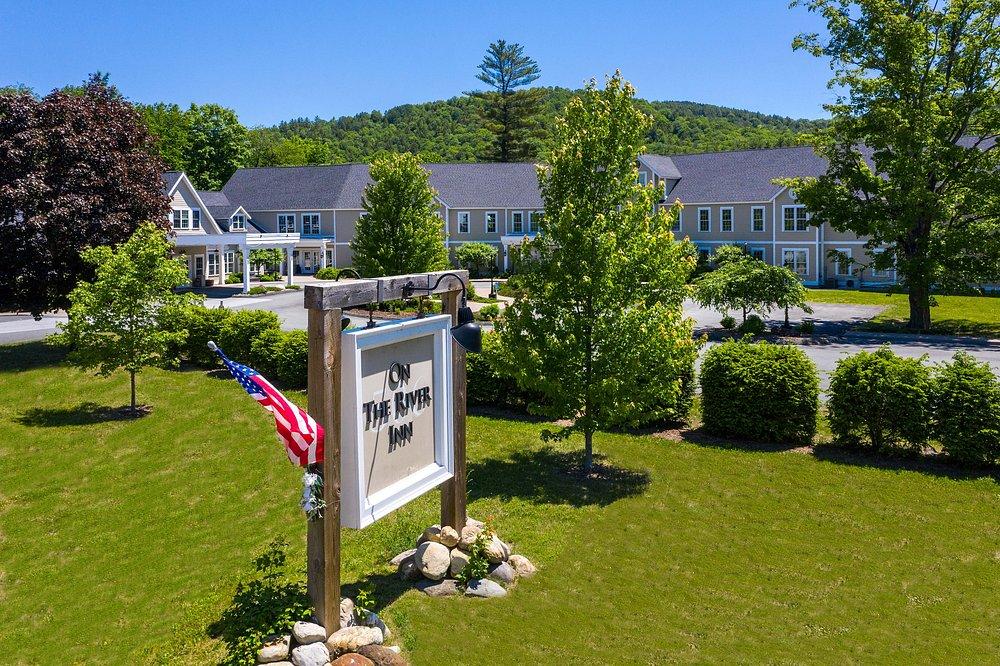 Hotel with a sign and American flag in a lush landscape on a clear day.