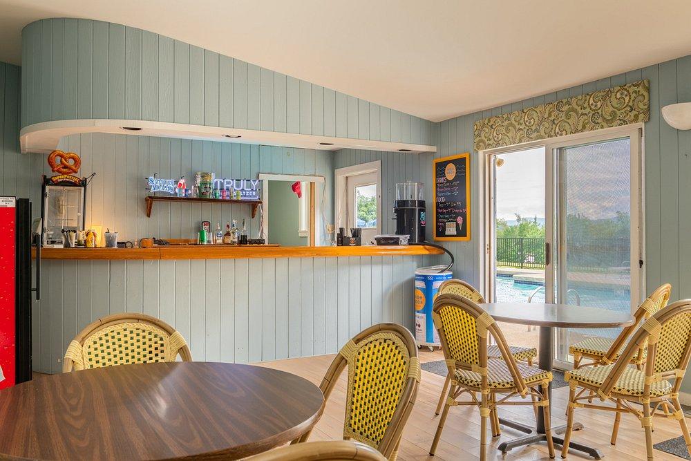 Cozy café interior with wicker chairs, counter, and pool view through window.