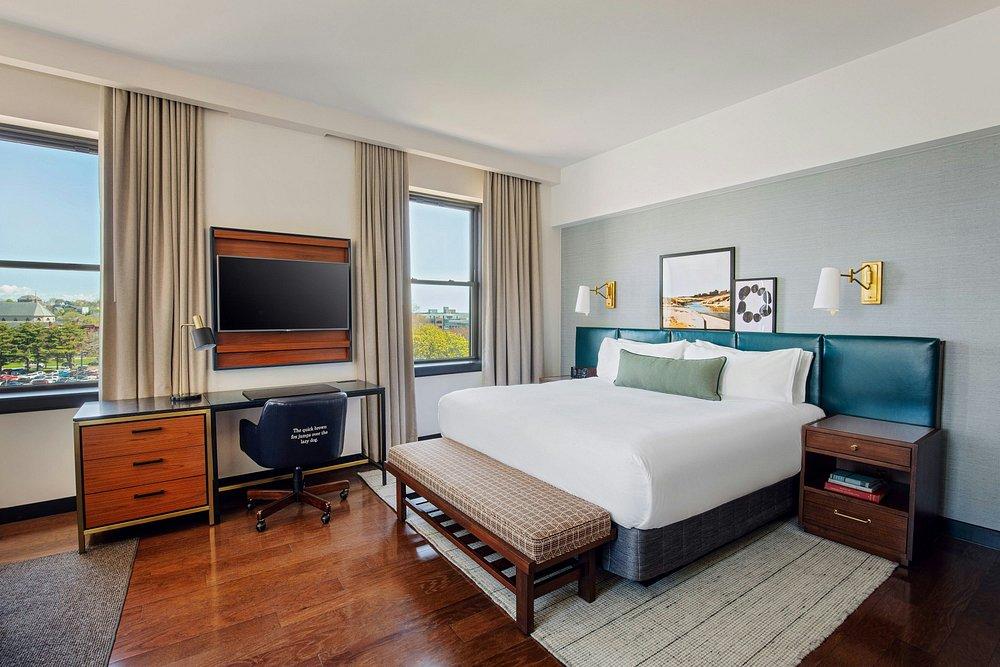 Cozy hotel room with a king bed, desk, and wall-mounted TV.