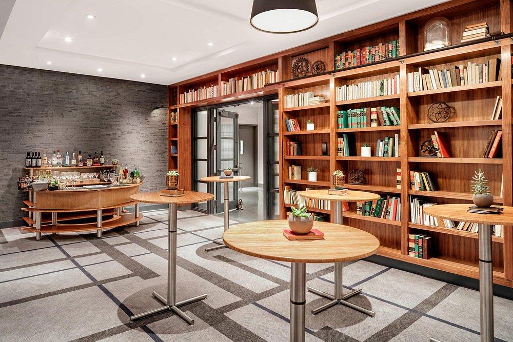 Library-themed room with wooden bookshelves and round tables.