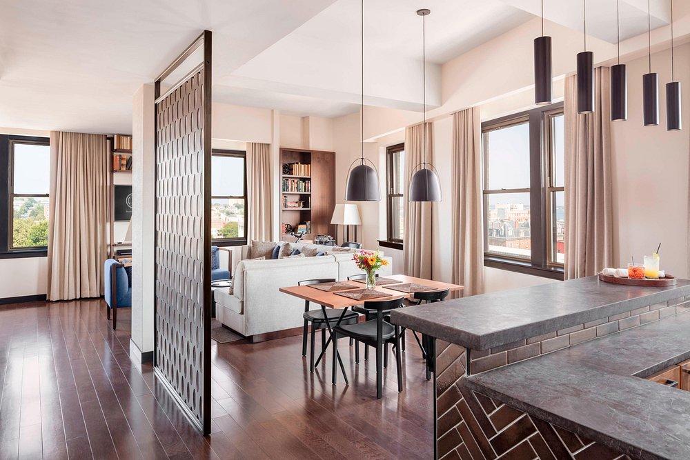 Open-plan modern living room with dining area, wooden floors, and ceiling lights.