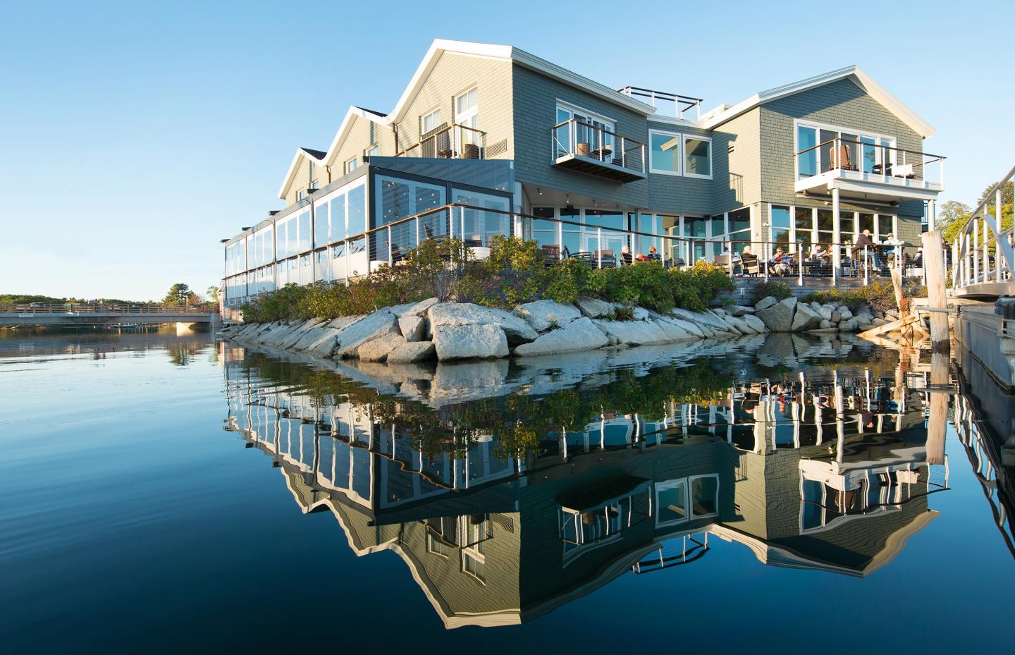 Modern building reflected in calm water under clear blue sky.