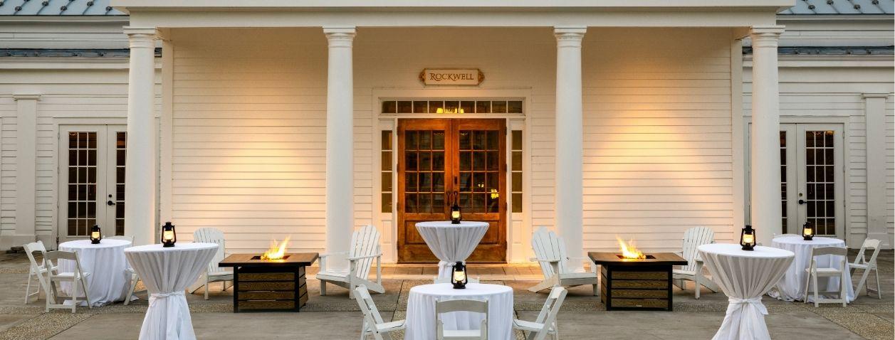 Elegant outdoor reception tables on a mansion terrace at dusk.