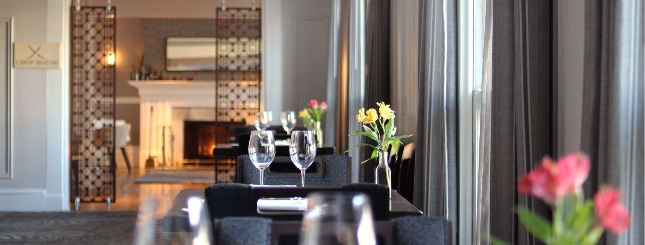 Elegant dining room with dark chairs, floral centerpiece, and pink tulips in foreground