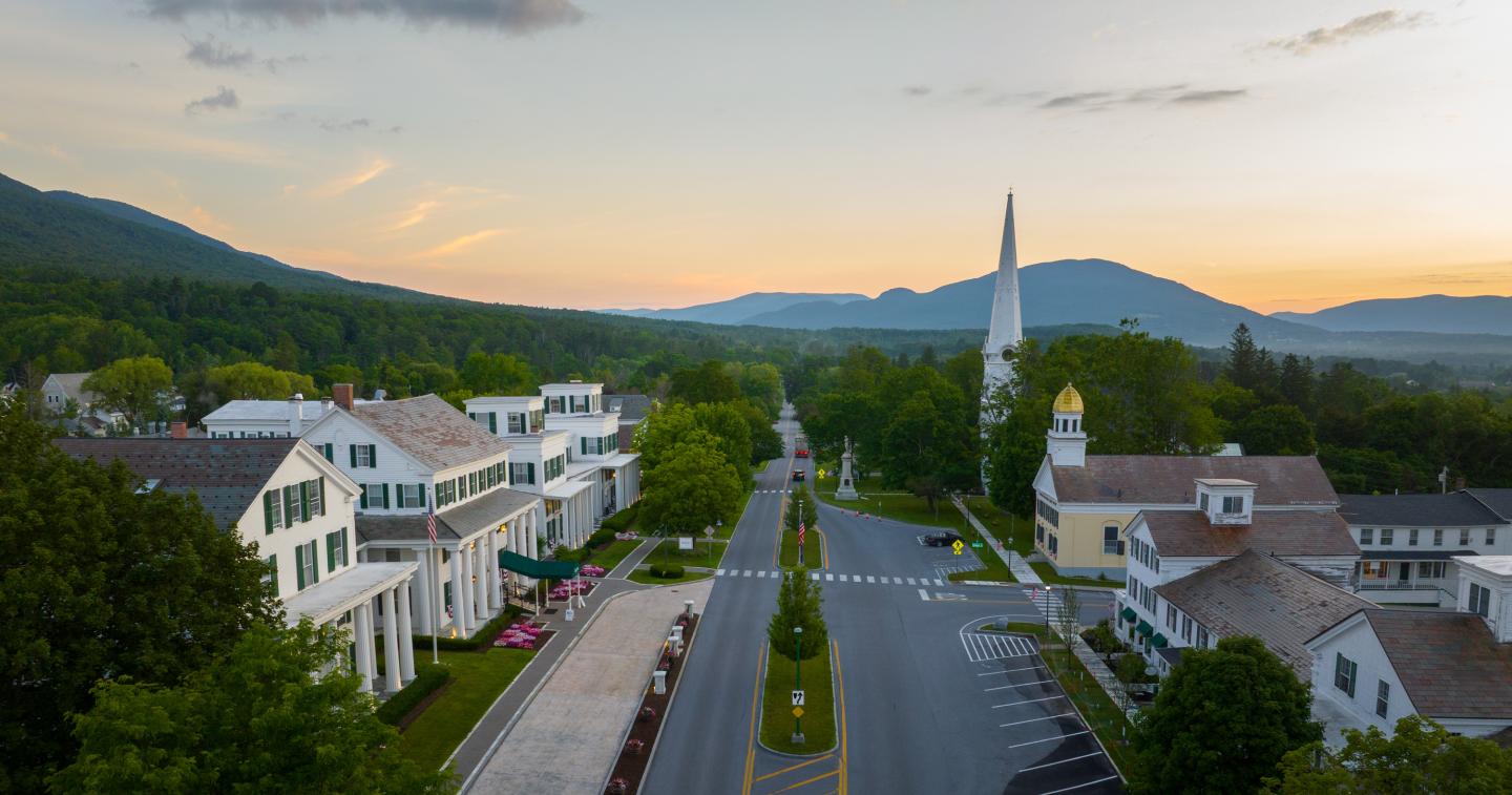 Aerial view of a small town street with a church steeple at sunset